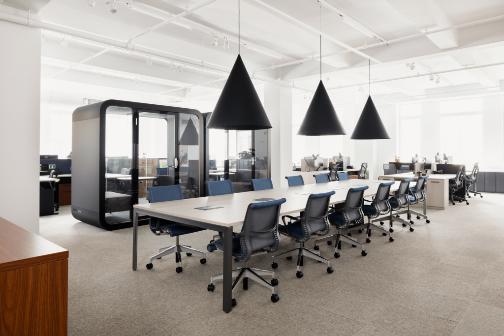 open floor at a university featuring a large table with chairs and two sound proof booths